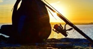 zaino e canna da pesca su scoglio al tramonto